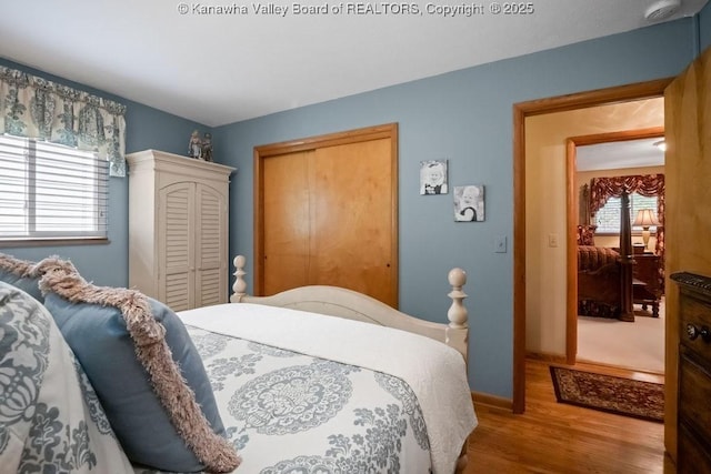 bedroom featuring baseboards, wood finished floors, and a closet
