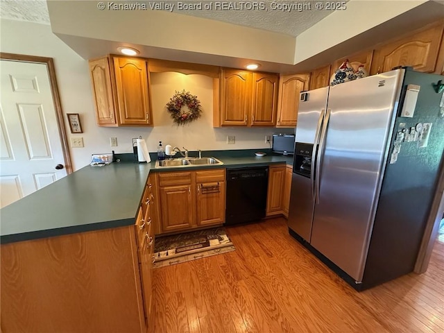 kitchen featuring a sink, dishwasher, stainless steel refrigerator with ice dispenser, and light wood-style floors
