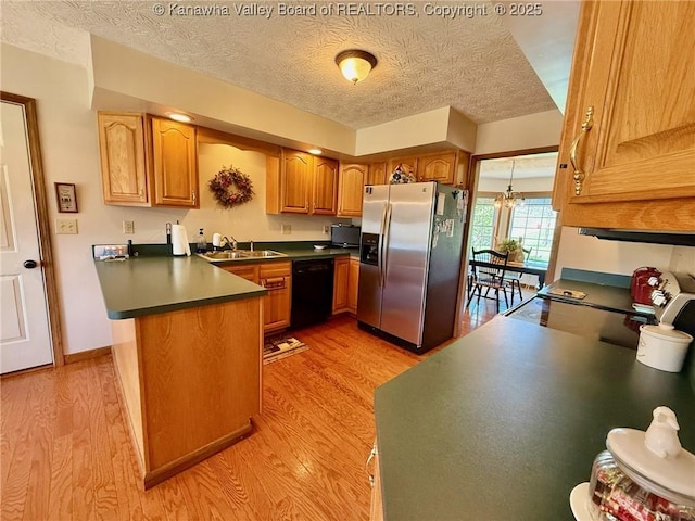 kitchen with dark countertops, light wood-style floors, dishwasher, a peninsula, and stainless steel fridge