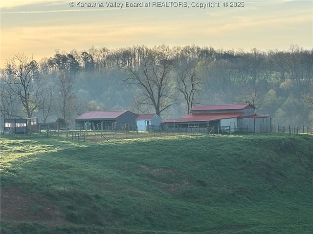 yard at dusk featuring fence, an outdoor structure, and a barn
