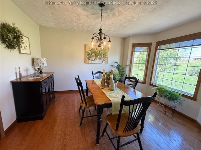 dining room featuring plenty of natural light, a textured ceiling, an inviting chandelier, and baseboards