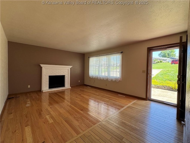 168 Jane Dr, Culloden, WV 25510 - unfurnished living room with a wealth of natural light, light wood-style floors, a textured ceiling, and a fireplace
