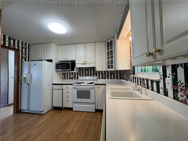 168 Jane Dr, Culloden, WV 25510 - kitchen featuring white cabinets, wallpapered walls, under cabinet range hood, wood finished floors, and white appliances