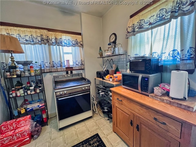 kitchen featuring brown cabinets, butcher block countertops, electric stove, stainless steel microwave, and light floors