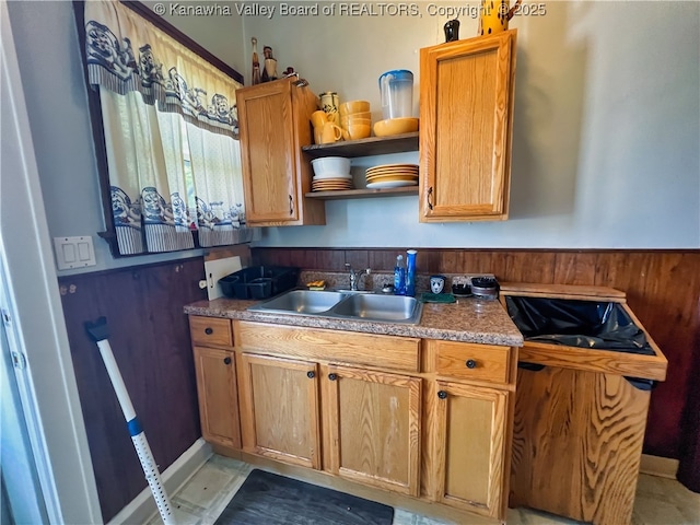 kitchen with a sink, dark countertops, open shelves, and brown cabinetry