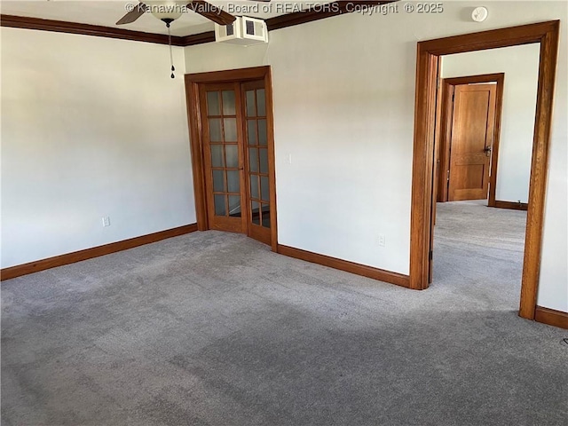 carpeted spare room featuring crown molding, baseboards, a ceiling fan, and visible vents
