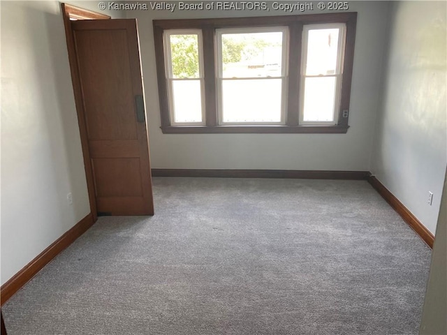 unfurnished room featuring carpet floors and baseboards