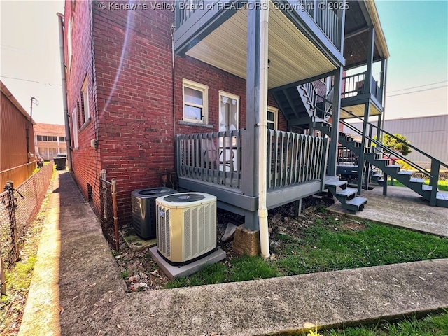 view of side of home featuring fence, central AC unit, and brick siding