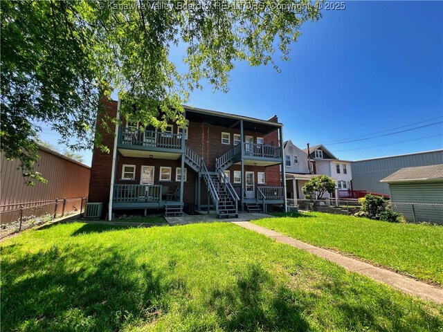 back of house with a lawn, brick siding, stairway, and a fenced backyard