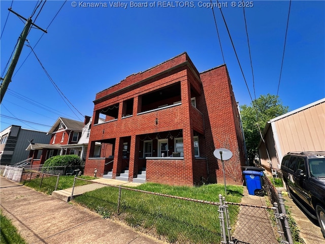 view of front of house with brick siding, a gate, a fenced front yard, and a balcony