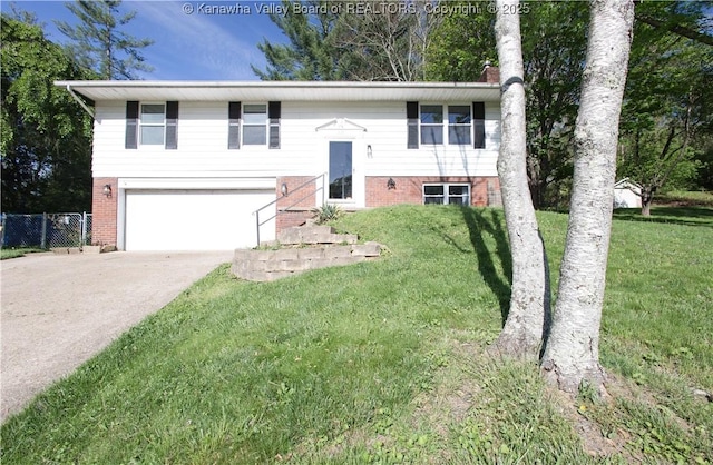 bi-level home with concrete driveway, brick siding, an attached garage, and a front yard
