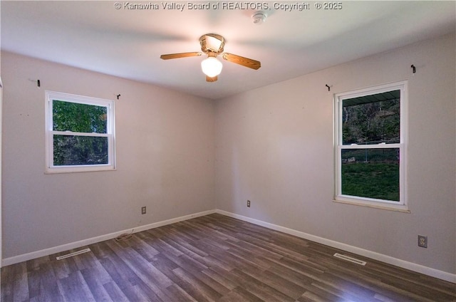 spare room featuring baseboards, ceiling fan, visible vents, and dark wood-type flooring