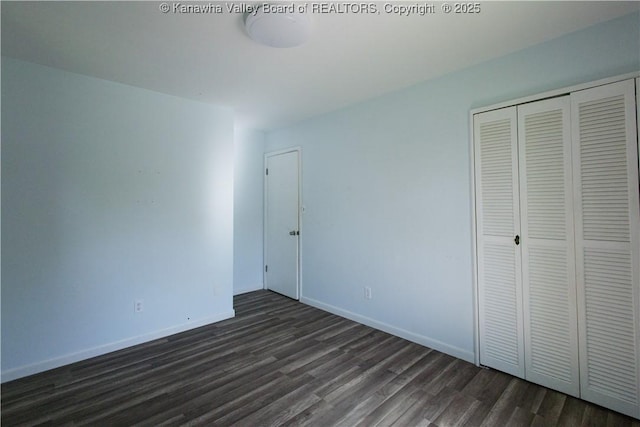 unfurnished bedroom with baseboards, a closet, and dark wood-style floors