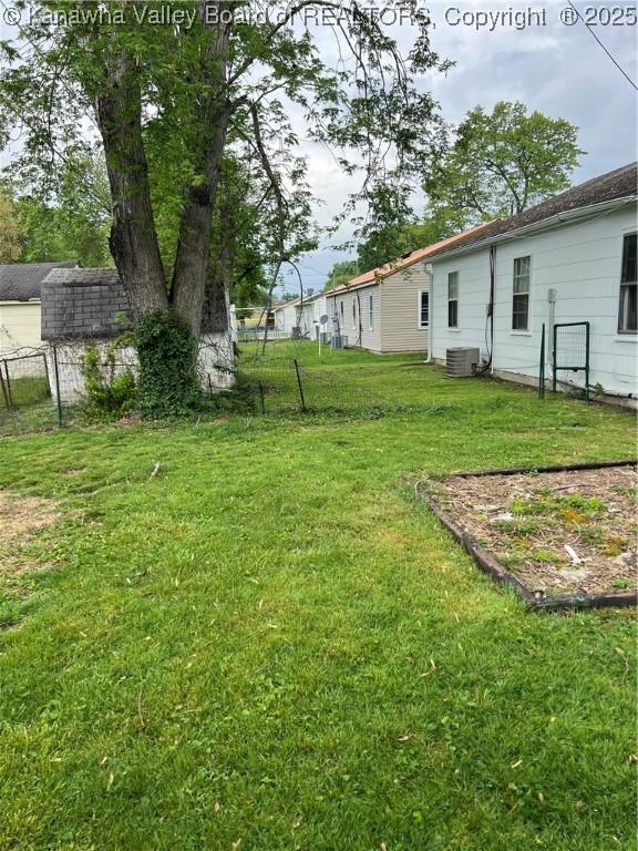 view of yard with central AC and fence