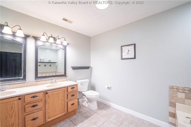 bathroom featuring toilet, a bathtub, double vanity, tile patterned flooring, and baseboards