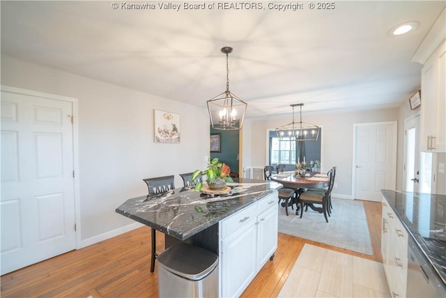 kitchen featuring a chandelier, white cabinetry, a breakfast bar area, decorative light fixtures, and light wood-type flooring