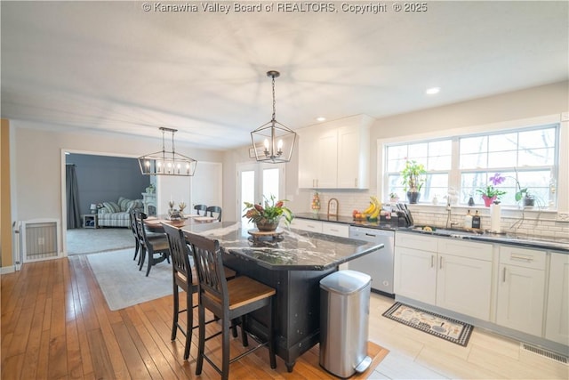 kitchen with dishwasher, a sink, a chandelier, decorative backsplash, and white cabinetry