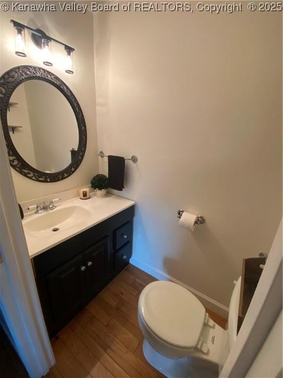 bathroom featuring hardwood / wood-style floors, vanity, baseboards, and toilet