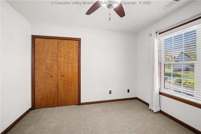 unfurnished bedroom with baseboards, a ceiling fan, a closet, and light carpet
