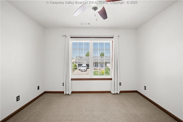 spare room featuring baseboards, ceiling fan, light colored carpet, and visible vents