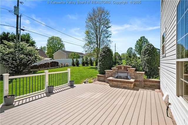 wooden terrace with fence, a yard, and a fireplace