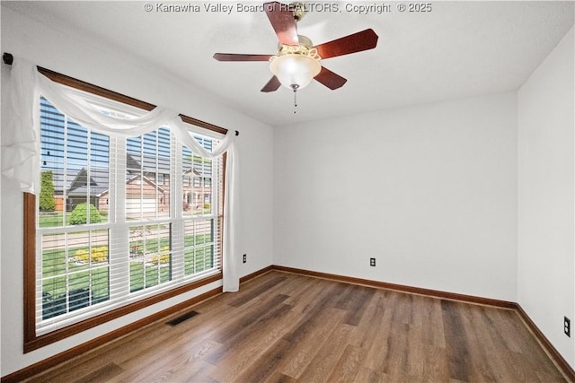 unfurnished room featuring a ceiling fan, baseboards, visible vents, and wood finished floors