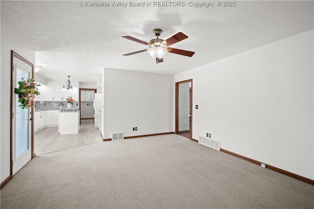 interior space featuring baseboards, light carpet, ceiling fan with notable chandelier, and visible vents