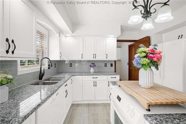 kitchen featuring white cabinets, backsplash, light stone counters, and a sink