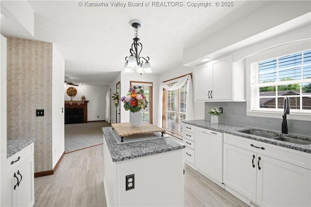 kitchen with light stone countertops, a center island, a sink, and dishwasher