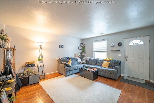 living area with baseboards, visible vents, and wood finished floors
