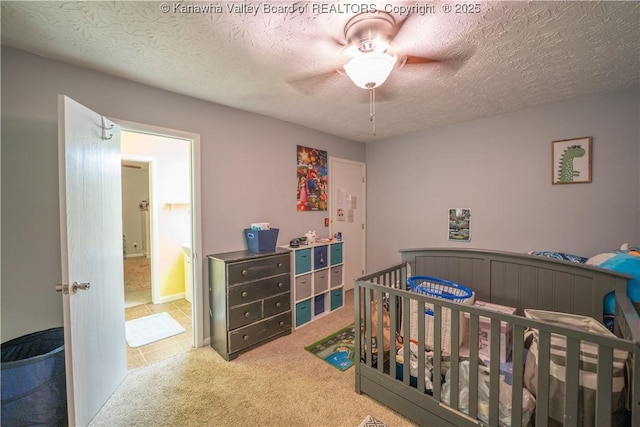 bedroom featuring a textured ceiling, a crib, and carpet