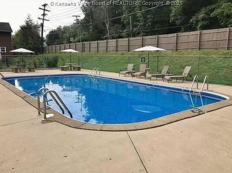 pool with a patio, a lawn, and fence