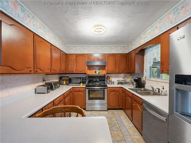 kitchen featuring a sink, appliances with stainless steel finishes, brown cabinets, and light countertops