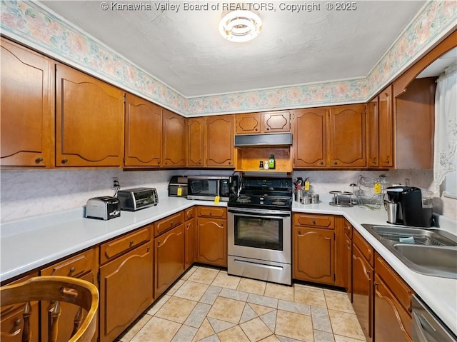 kitchen with light tile patterned floors, appliances with stainless steel finishes, and brown cabinetry