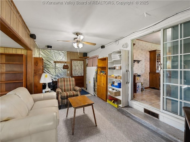 carpeted living room with visible vents, ceiling fan, and wallpapered walls