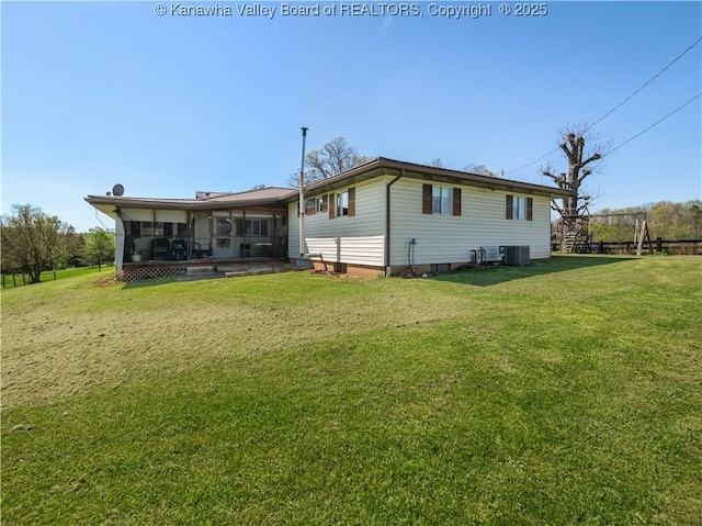 rear view of property with central air condition unit, a lawn, and a sunroom