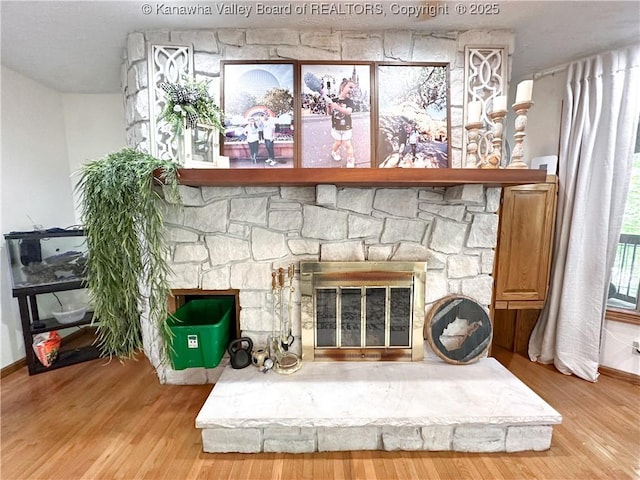 room details with baseboards, a stone fireplace, and wood finished floors