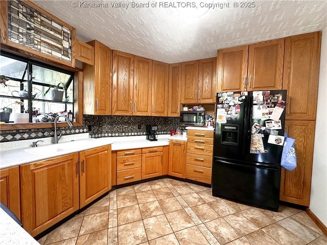 kitchen with backsplash, a sink, black appliances, and light countertops