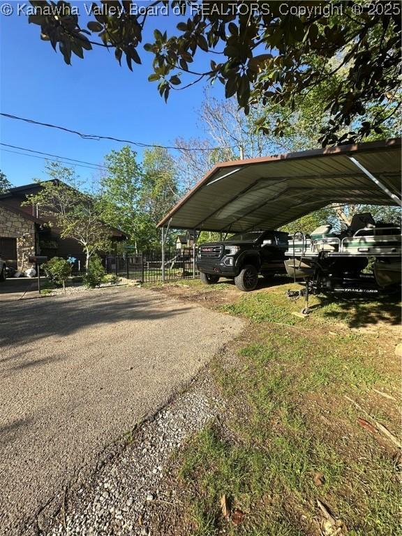 view of vehicle parking featuring fence and a carport