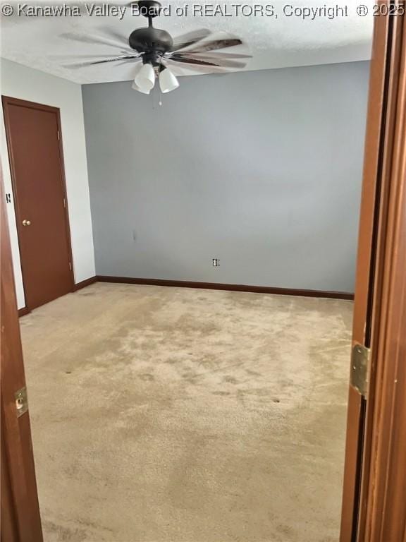 spare room featuring carpet floors, ceiling fan, and baseboards