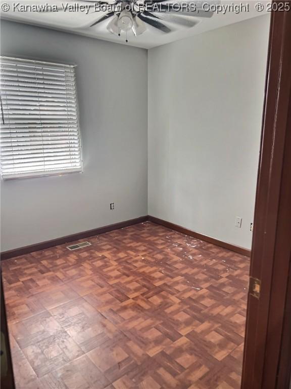 empty room with baseboards, ceiling fan, and visible vents
