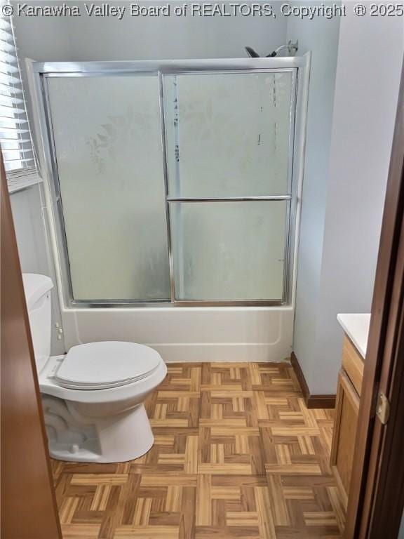 full bath featuring vanity, baseboards, toilet, and shower / bath combination with glass door