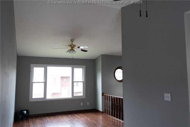 spare room with baseboards, ceiling fan, and dark wood-style flooring