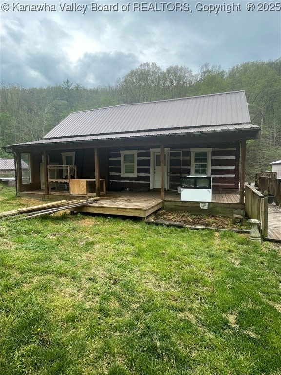 back of property featuring covered porch, a yard, and metal roof