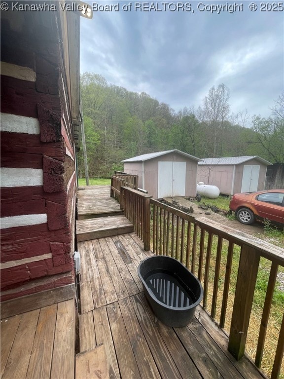 deck featuring an outdoor structure, a shed, and a forest view