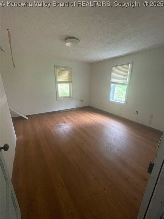 spare room featuring plenty of natural light, a textured ceiling, and wood finished floors
