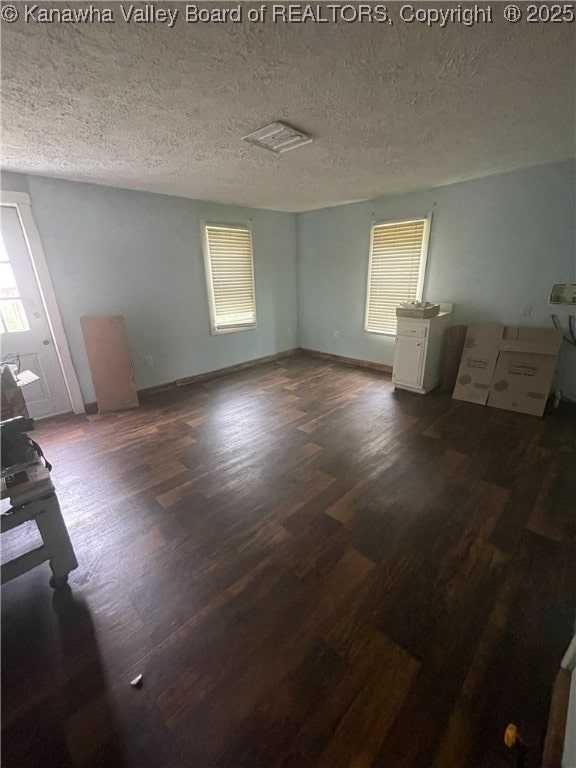 spare room with a textured ceiling and dark wood-style floors