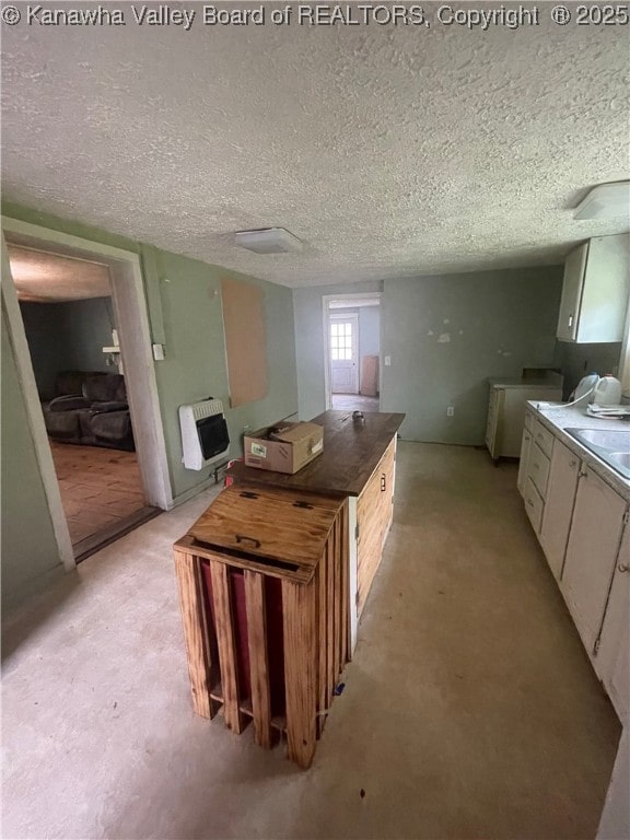 kitchen featuring heating unit, light colored carpet, a textured ceiling, and washer and clothes dryer