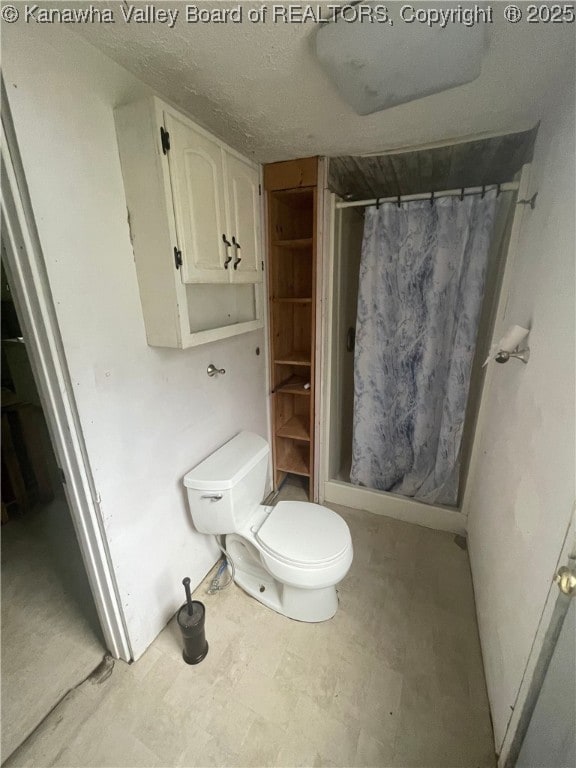 bathroom featuring tile patterned floors, a stall shower, and toilet