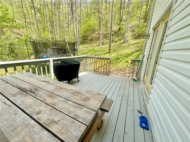 wooden terrace with a trampoline and a grill